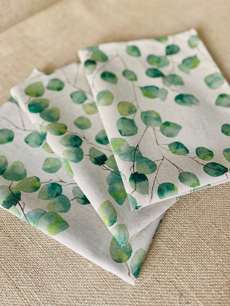 Eucalyptus print linen kitchen towels with green leaves and beige natural linen background