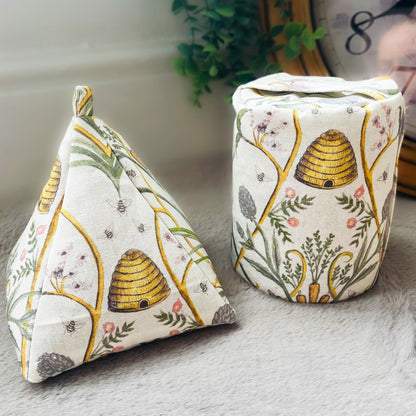 “Two handmade doorstops featuring Angel Strawbridge Chateaux fabric. One is a triangular shape and the other is a cylindrical shape, both adorned with a charming bee and floral pattern.”