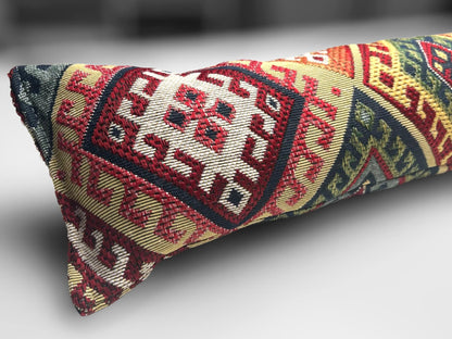 Handmade kilim fabric draught excluder in red, green, and beige tones, designed to block cold air under doors.