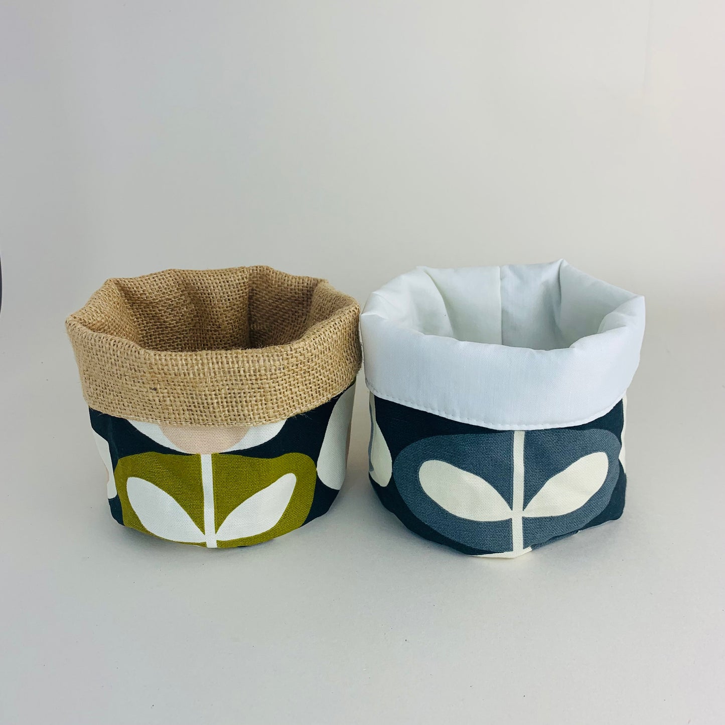 Orla Kiely fabric plant pots and storage baskets in grey and olive, lined with linen or hessian. These versatile containers feature retro-inspired patterns, perfect for adding a stylish touch to your home decor while providing practical storage solutions