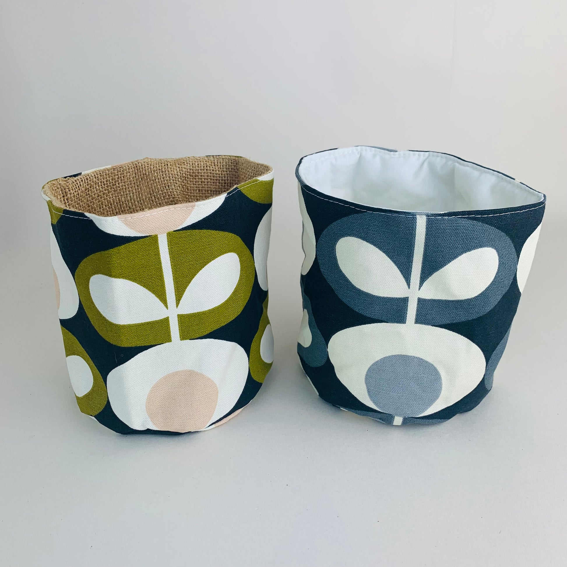 Orla Kiely fabric plant pots and storage baskets in grey and olive, lined with linen or hessian. These versatile containers feature retro-inspired patterns, perfect for adding a stylish touch to your home decor while providing practical storage solutions