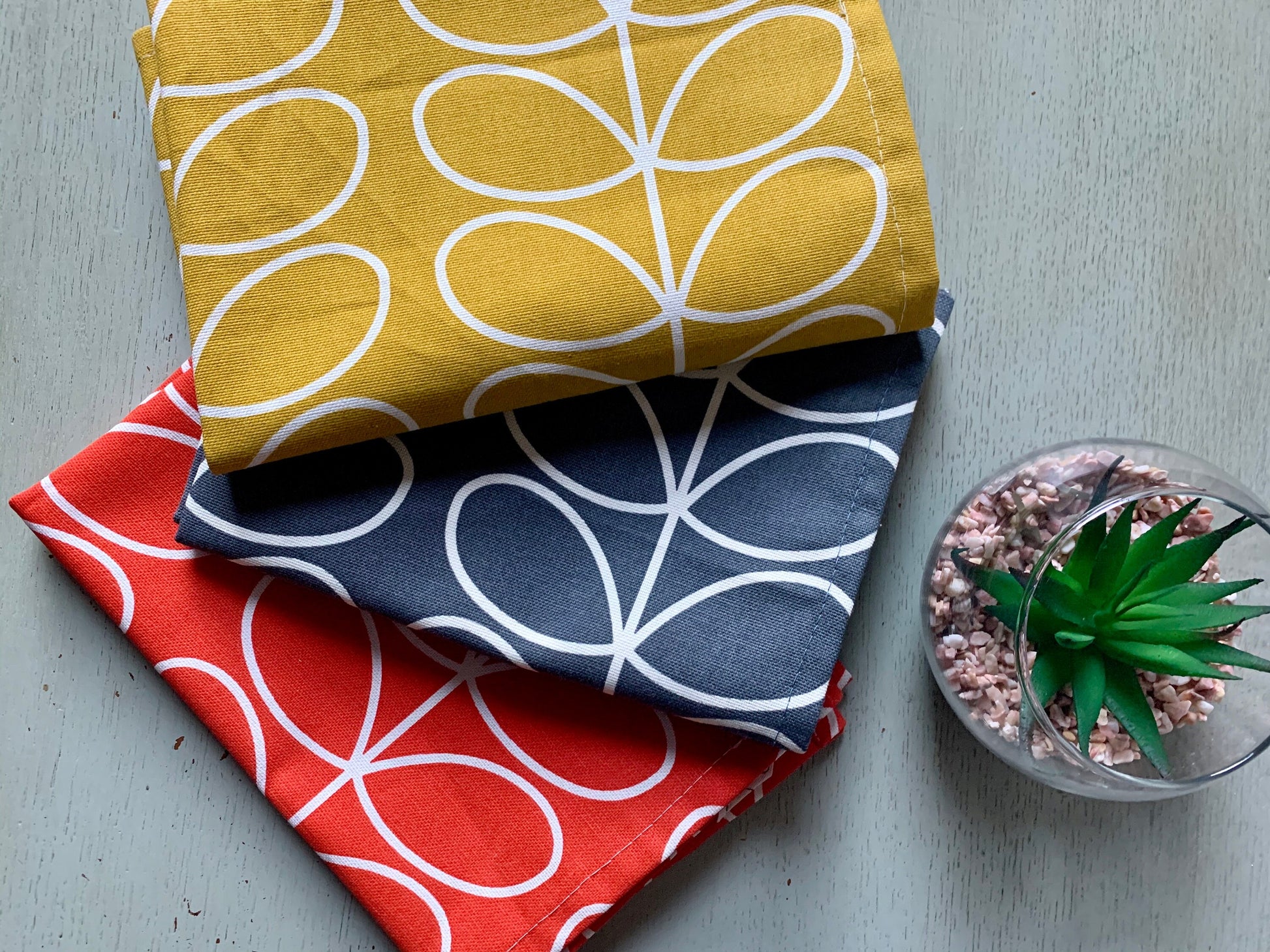 Set of three Orla Kiely kitchen towels featuring a stylish design in grey, red, and yellow. Each towel showcases a distinct retro-inspired pattern, perfect for adding a pop of color and contemporary flair to your kitchen decor.