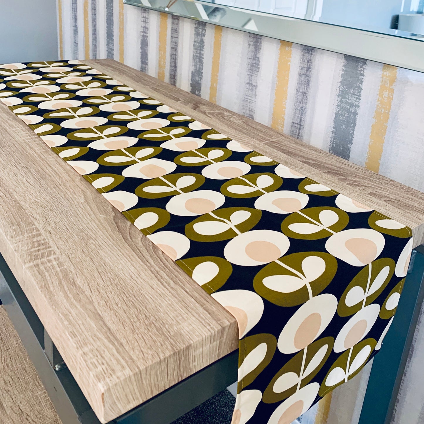 Orla Kiely olive oval table runner featuring a bold, retro-inspired pattern in olive green. Available in multiple lengths, this stylish table runner adds a touch of modern elegance to any dining setting. Perfect for bringing a pop of color and sophisticated design to your home decor.