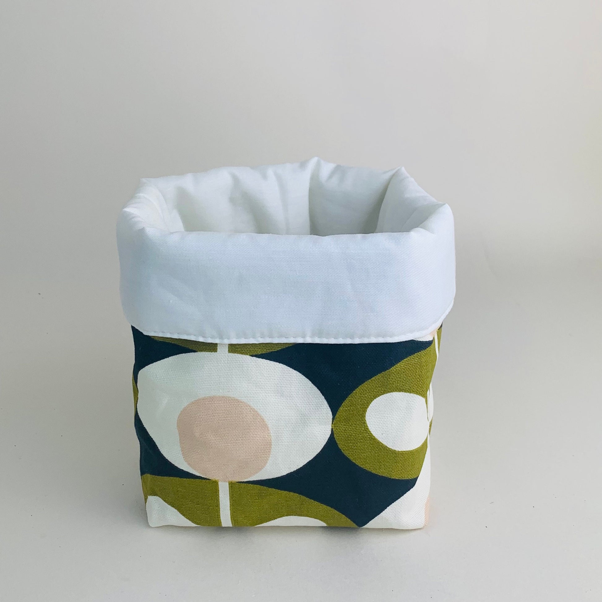 Orla Kiely fabric plant pots and storage baskets in grey and olive, lined with linen or hessian. These versatile containers feature retro-inspired patterns, perfect for adding a stylish touch to your home decor while providing practical storage solutions