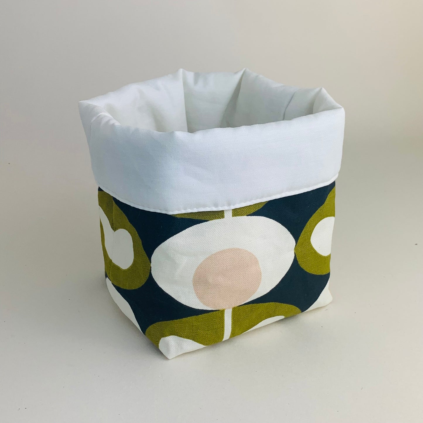 Orla Kiely fabric plant pots and storage baskets in grey and olive, lined with linen or hessian. These versatile containers feature retro-inspired patterns, perfect for adding a stylish touch to your home decor while providing practical storage solutions